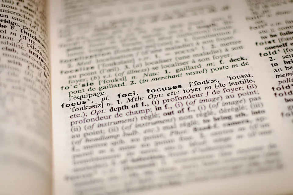 Close-up of an open dictionary, its dense columns of entries in sharp focus around the word focus