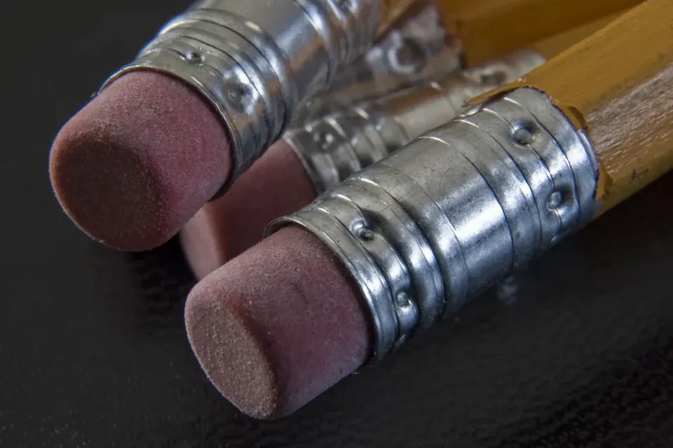 Close-up of two yellow wooden pencils with worn pink erasers held in metal ferrules